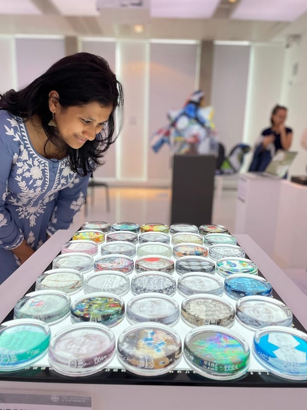 Someone peering over an artwork installation which is of several glass paperweight, all with images behind them, placed on top of a light table.